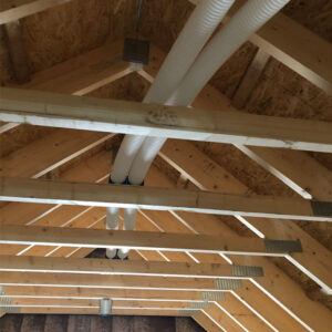 An attic with wooden beams and two white plastic pipes running along the top of the roof.
