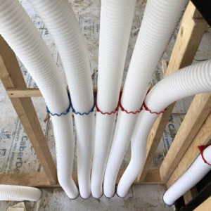 A row of white PVC pipes running through wooden beams.
