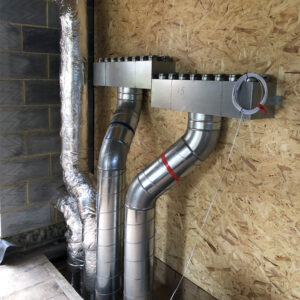 A close-up view of a ventilation system in a building under construction. The system consists of exposed metal pipes.