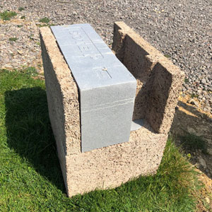 A single concrete block sitting on top of a grassy field. The grass is a light green.